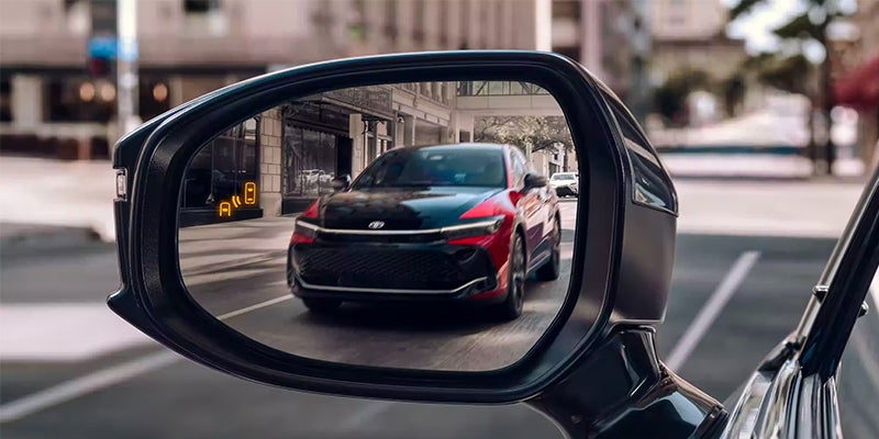 A Toyota Crown seen reflected in a side mirror