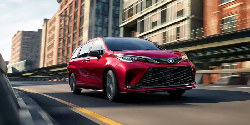 A red Toyota Sienna driving through a city,