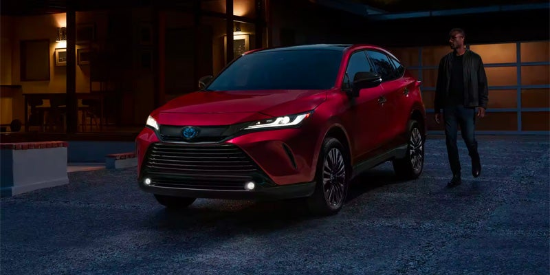 A man walks out to his red Toyota Venza parked in a driveway