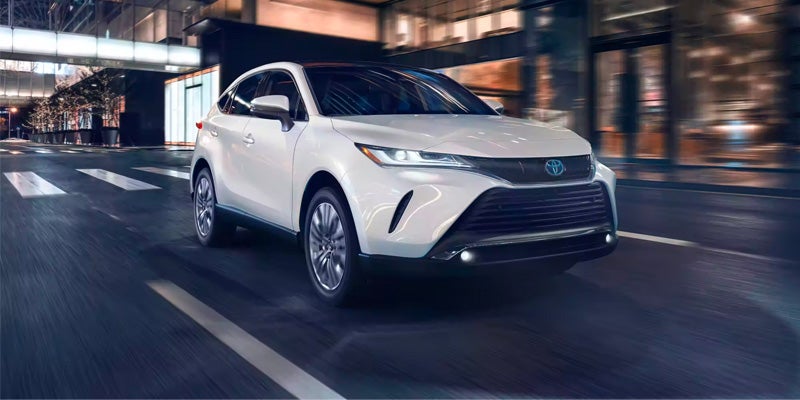 A white Toyota Venza drives through a city at night