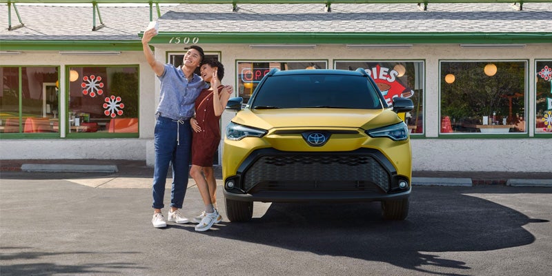 A couple takes a photo with their Toyota Corolla Cross