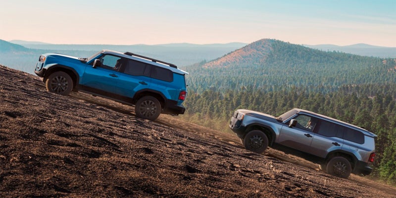 Two Toyota Land Cruisers driving up a steep hill
