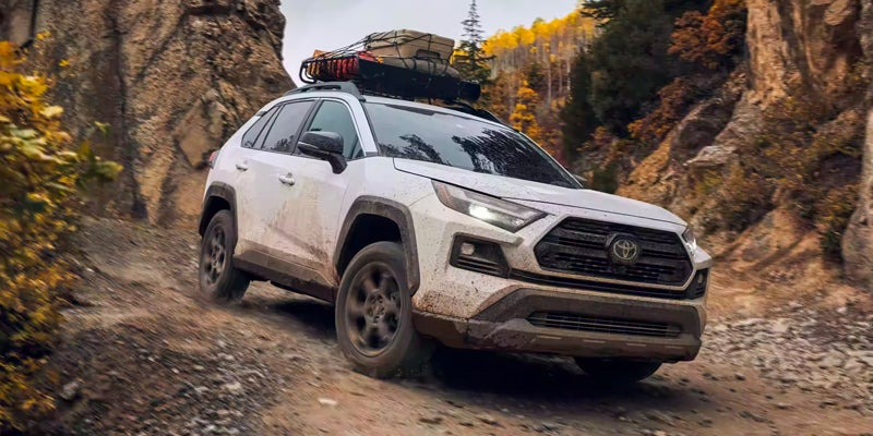 A white Toyota RAV4 drives down a rocky road