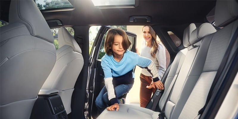 A child climbs into the backseat of a Toyota bZ4X